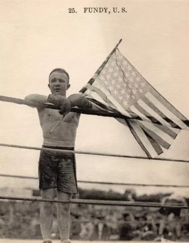 A boxer leaning on the ropes holding an American Flad
