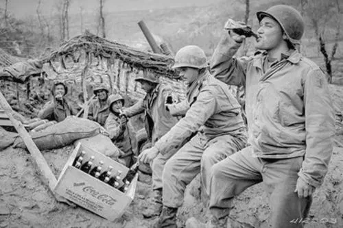 Men of the 133rd Field Artillery Battalion enjoy Cokes on the front, March 17, 1944. (Records of the Office of the Chief Signal Officer, National Archives)